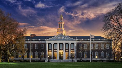 Front view of Harvard Business School at sunset, featuring the iconic Baker Library building, American flags, and dramatic evening sky — symbolizing academic excellence and leadership.| Abhishek Tanwar| Mel Robbins