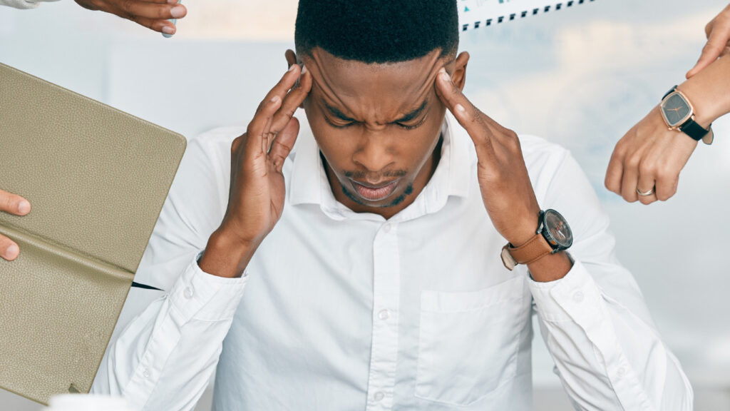 Stressed office employee overwhelmed by multiple tasks and coworkers, showing signs of anxiety and workplace burnout. Abhishek tanwar | xpodcasts